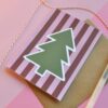 Kerstkaart met een illustratie van een kerstboom en een achtergrond van roze en rode strepen. Deze kerstkaart heeft een moderne en grafische look.