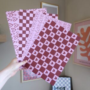 Setje van vier verschillende vellen papier met ieder een eigen illustratie die met Valentijn te maken heeft, bedoelt om te scrapbooken of te journallen. De kleuren die zijn gebruikt zijn roze en rood.