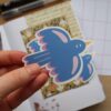Losse glossy vinyl sticker van een blauwe vogel met roze details.