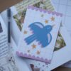Ansichtkaart met een illustratie van een blauwe vogel en sterretjes.