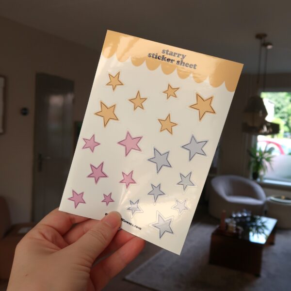 Een hand die een stickervel met sterretjes vast houdt.