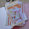 Een afbeelding van een lente journal kit vol met papiertjes en stickers bedoelt om mee te journallen of te scrapbooken.