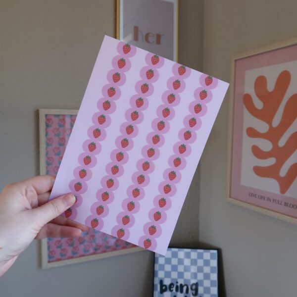 Een vel papier met een roze achtergrond en een patroon van aardbeien, bedoelt voor het journallen of scrapbooken.