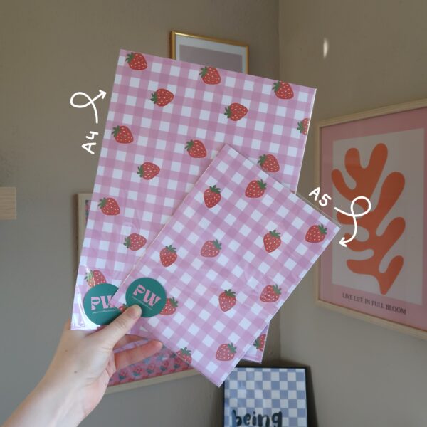 Twee papier bundels met patronen van aardbeien en roze gingham patroon, maat A4 en A5.