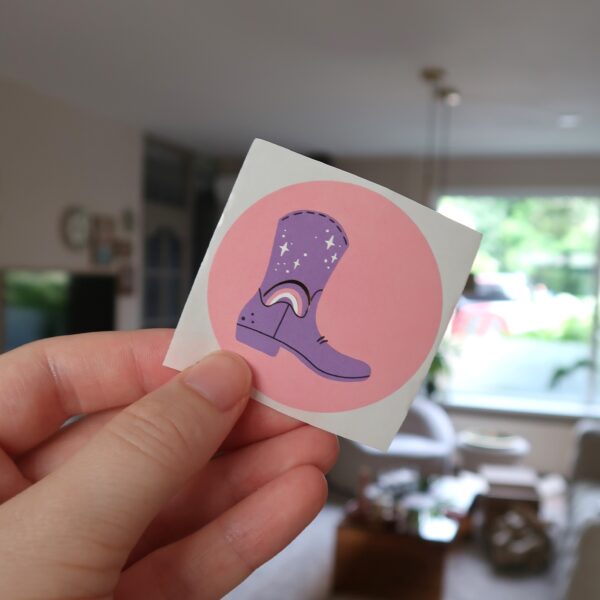 Een roze ronde sticker met een cowboy laars.
