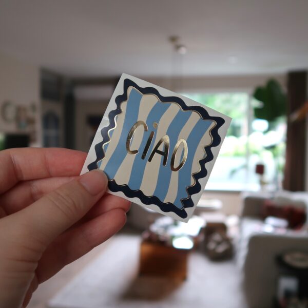Vierkante sticker met gouden details en de tekst ciao