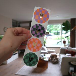 Setje van vier ronde stickers met een grid patroon in verschillende kleurtjes en een gouden hartje