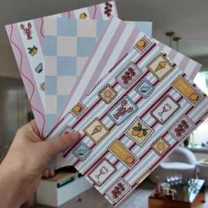 Papier bundel met eigen geïllustreerd papier met afbeeldingen in een zomerse stijl, zoals ijsjes, citroenen en schelpjes.