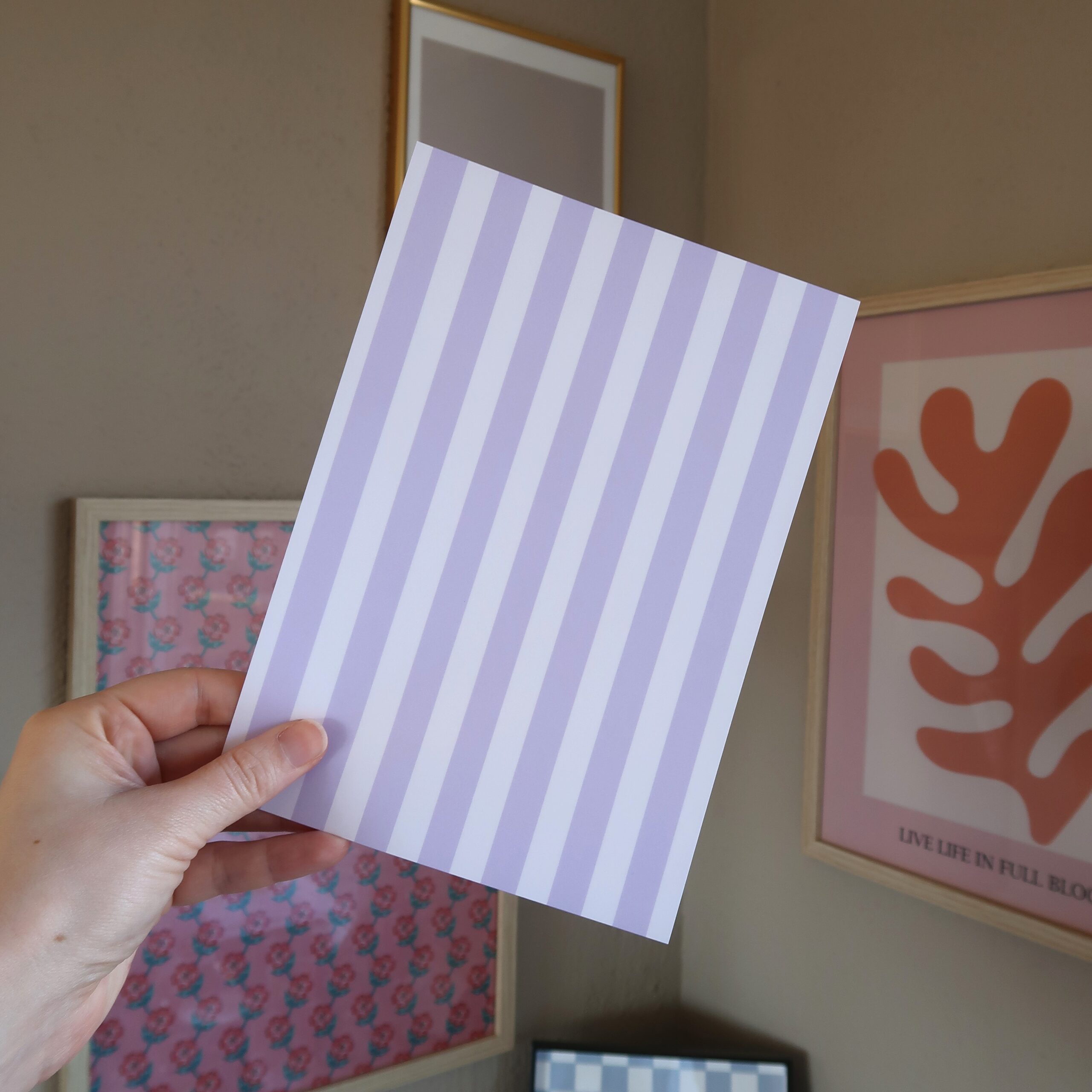 Een hand die een vel papier vast houdt met lila en witte strepen.