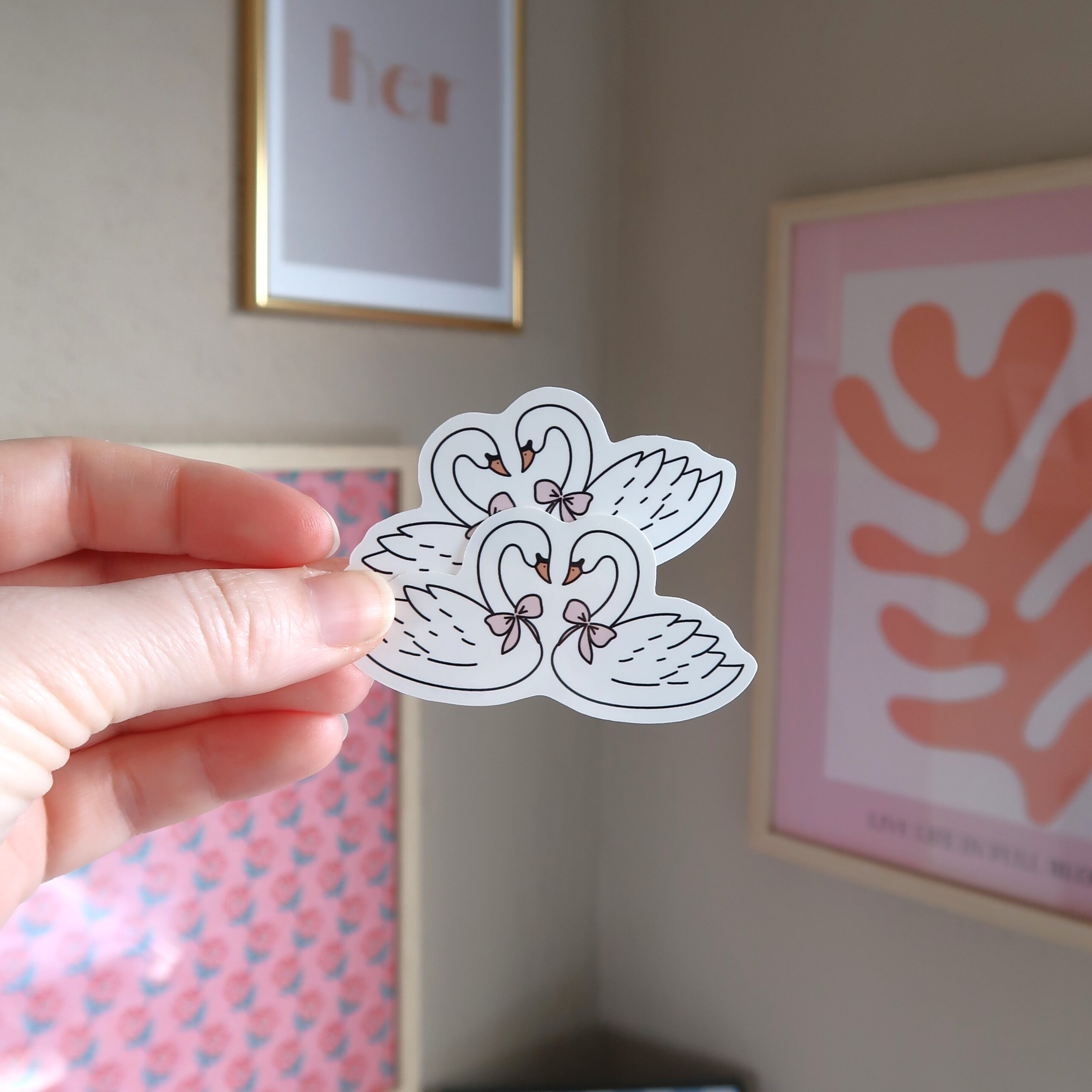 Hand die twee losse stickers vast houdt met een illustratie van twee verliefde zwanen